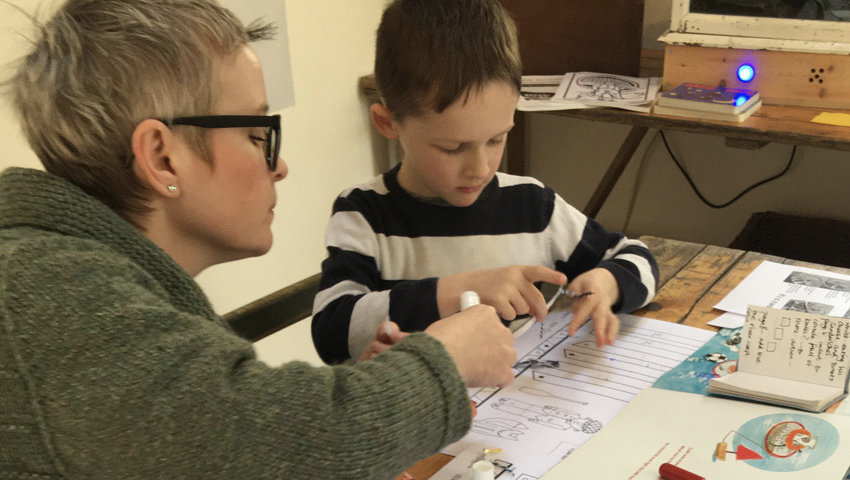 Image of a lady and a young boy doing a print and cut out activities.